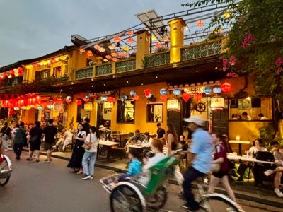 Vibrant street scene with lanterns and rickshaws at dusk.
