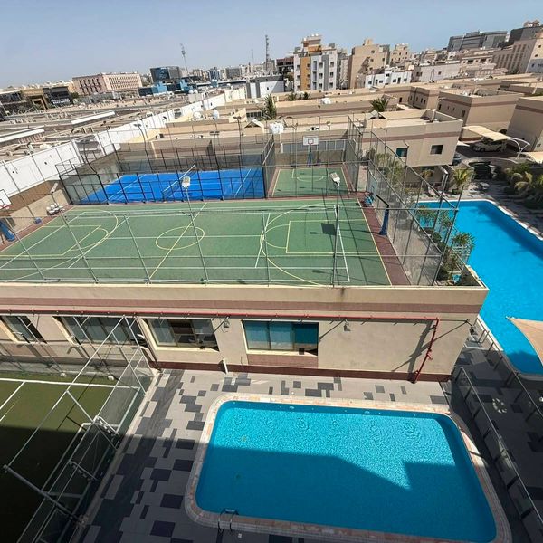 A rooftop sports complex with basketball and tennis courts, plus two swimming pools.
