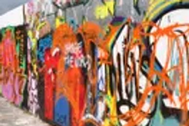 A colorful graffiti-covered wall stretches under a partly cloudy sky.