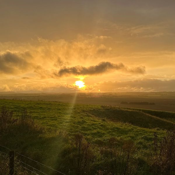 Sunset casting golden light over a green countryside landscape.