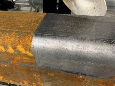 A metal surface partially cleaned by laser, showing clear contrast between rusty and cleaned areas.