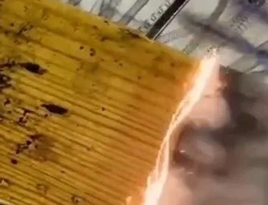 A wooden plank partially burning with smoke rising.