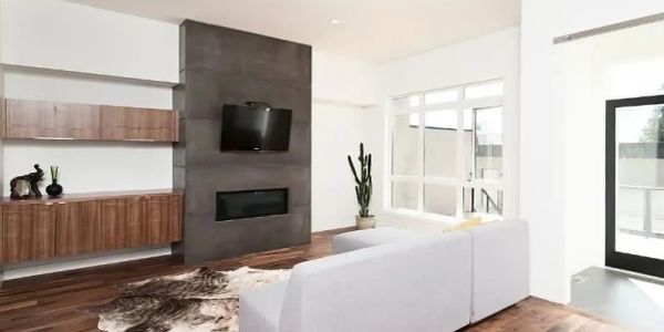 Modern living room with white sofa, wood flooring, and mounted TV.