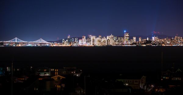 San Francisco skyline illuminated at night with the Bay Bridge glowing.