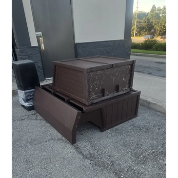 Two stacked brown plastic outdoor storage boxes on pavement.