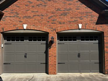 Stamped carriage garage doors with windows and decorative hardware installed in South Forsyth County