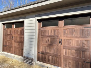 Wood-look carriage-style garage doors with decorative hardware installed in Dawsonville, GA by BB Ga