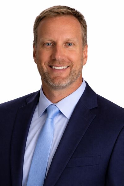 Smiling man in business suit with light blue tie.