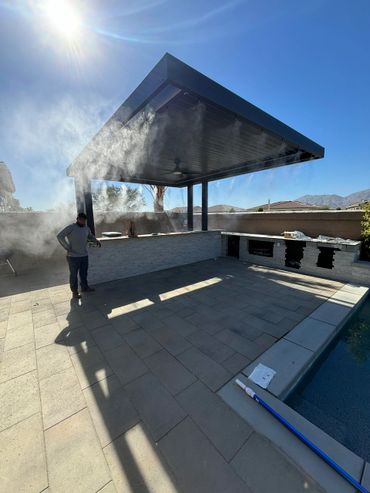 Outdoor misting system under a patio cover on a sunny day.