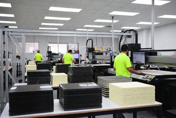 Workers at Alienhead using machines in a factory with stacked core materials.