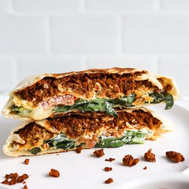 A stuffed pita bread with seasoned minced filling and fresh greens.
