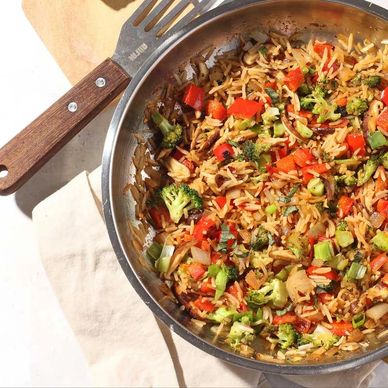 Colorful vegetable fried rice in a stainless steel pan.