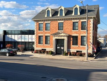 Historic brick library building with modern glass extension under a blue sky.