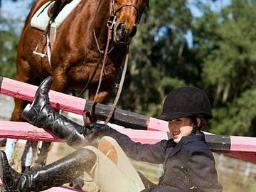 Young rider falls off horse during equestrian event.