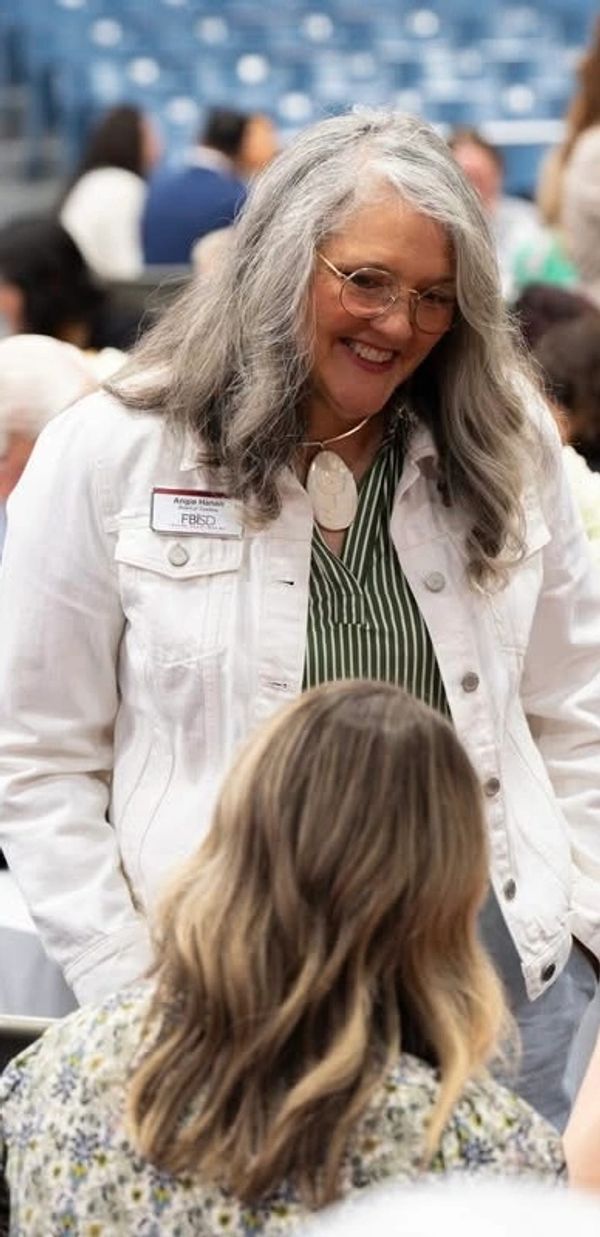 Woman with gray hair smiling and chatting with another person.