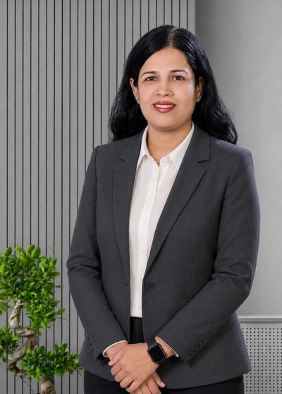 Professional woman in a dark blazer and white shirt standing confidently indoors.