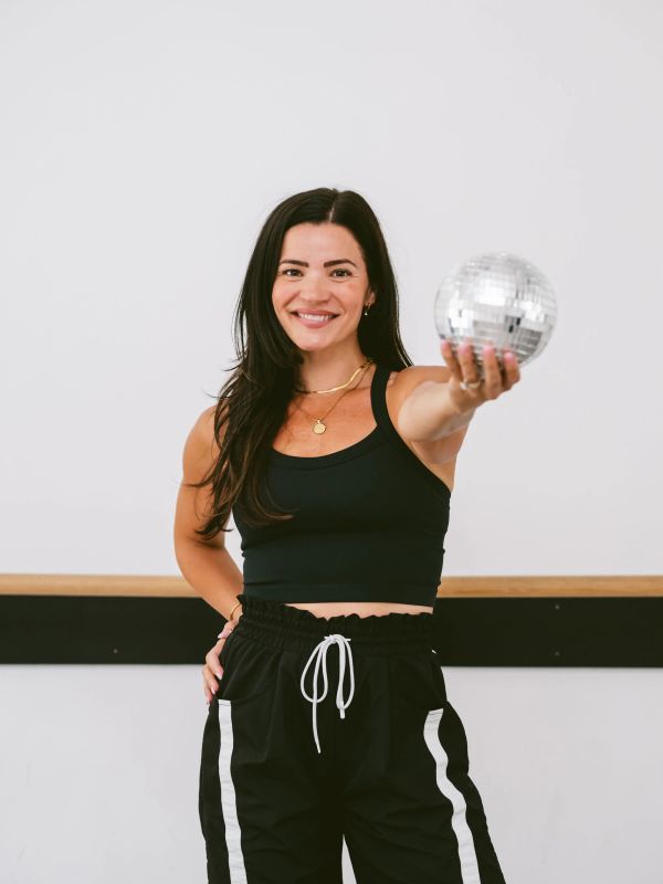 Smiling woman in black holding a disco ball.