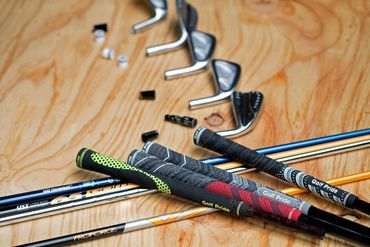 Golf club heads and shafts arranged on a wooden surface.