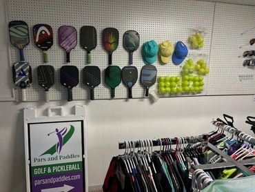 Pickleball paddles, balls, and apparel displayed in a sports store.