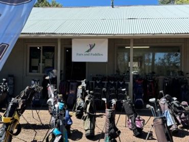 Outdoor display of golf bags in front of a building with a 'Forward Fairways' sign.