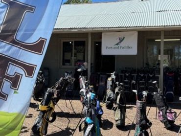 Golf clubs displayed outside a building with a sign reading 'Porks and Puddles'.