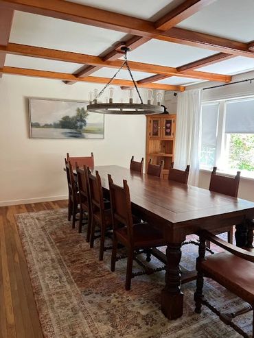 Elegant dining room with wooden table and chairs under rustic chandelier.