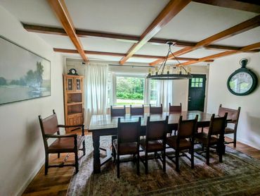 Spacious dining room with wooden beams and large table.