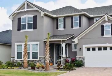Modern two-story house with gray exterior and palm trees.
