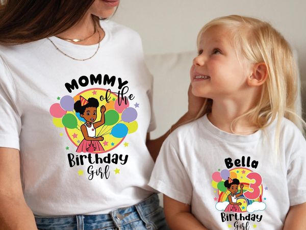 Mother and daughter wearing matching birthday-themed t-shirts with colorful cartoon designs.