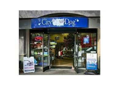 Entrance of City Dog pet store with open glass doors and signs outside.