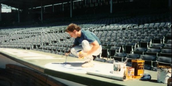 *Robert Ryan painting the All-Star logo on the National League Dugout at Wrigley Field in 1990.* 