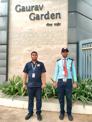 Two uniformed security guards standing in front of Gaurav Garden entrance.