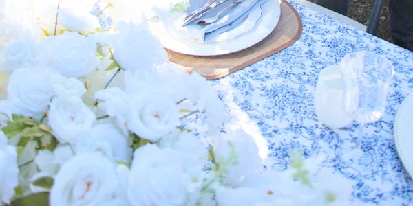 Elegant table setting with white roses and floral tablecloth.