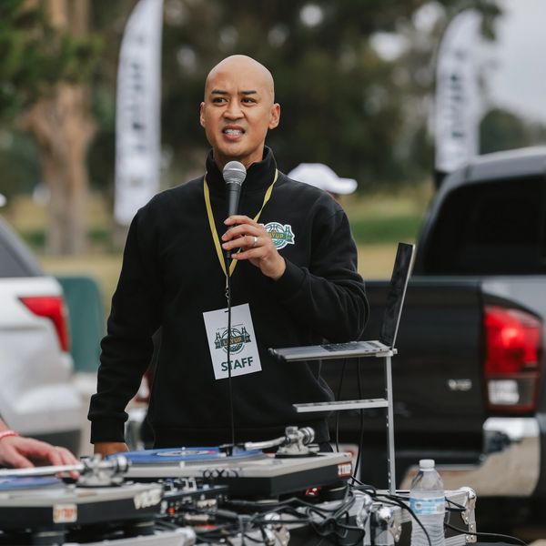 Man speaking into a microphone at an outdoor event.