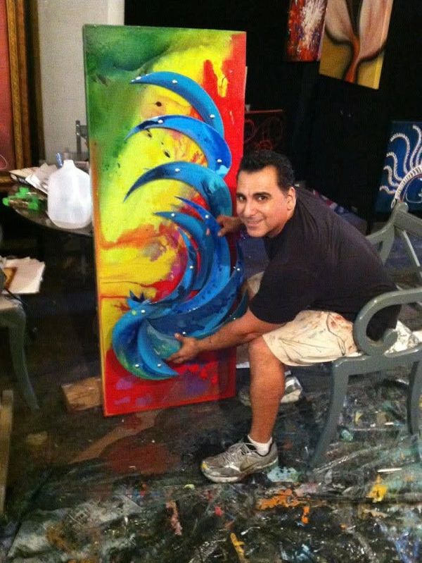 Artist showcasing a colorful wave-inspired painting in a vibrant studio.
