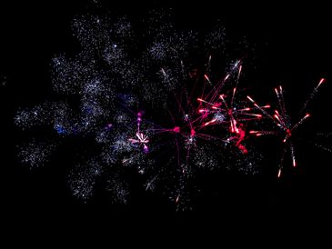 Bright red and white fireworks explode against a black night sky.