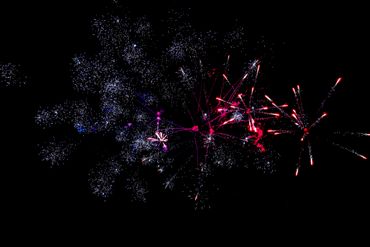 Bright red and white fireworks explode against a black night sky.