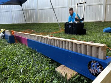 A long row of fireworks tubes set up outdoors on grass.