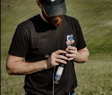 Man in black shirt and cap preparing a firework outdoors.