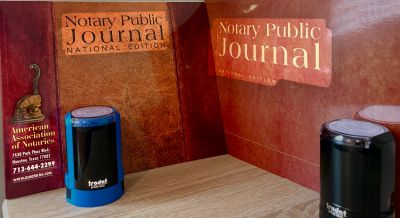 Two notary stamps on a wooden surface with a notary journal background.