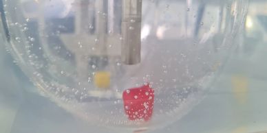 Red object submerged in water with bubbles around.