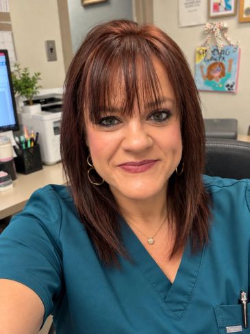 Woman in teal scrubs smiling at the camera.