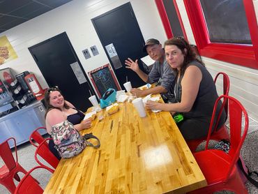 Three people enjoying a meal together at a casual restaurant with red chairs.