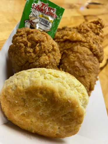 A meal with fried chicken, biscuit, and creole seasoning packet.