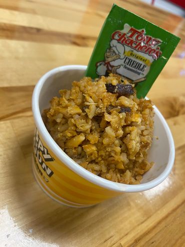 A cup of seasoned rice with a packet of Tony Chachere's Creole seasoning.