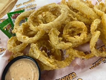 Crispy golden fried onion rings with a dipping sauce.