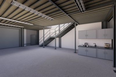 Empty industrial space with a staircase and kitchenette area.