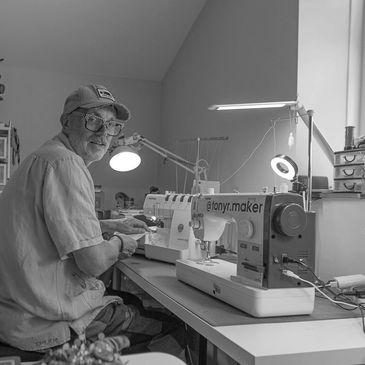 Man working on a sewing machine in a bright, organized craft room.
