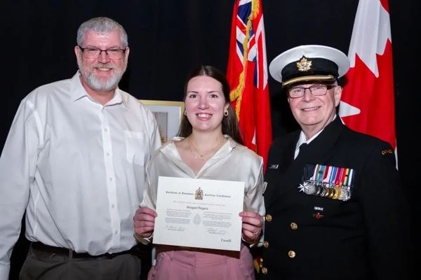 Three people pose with a certificate, two men and one woman.