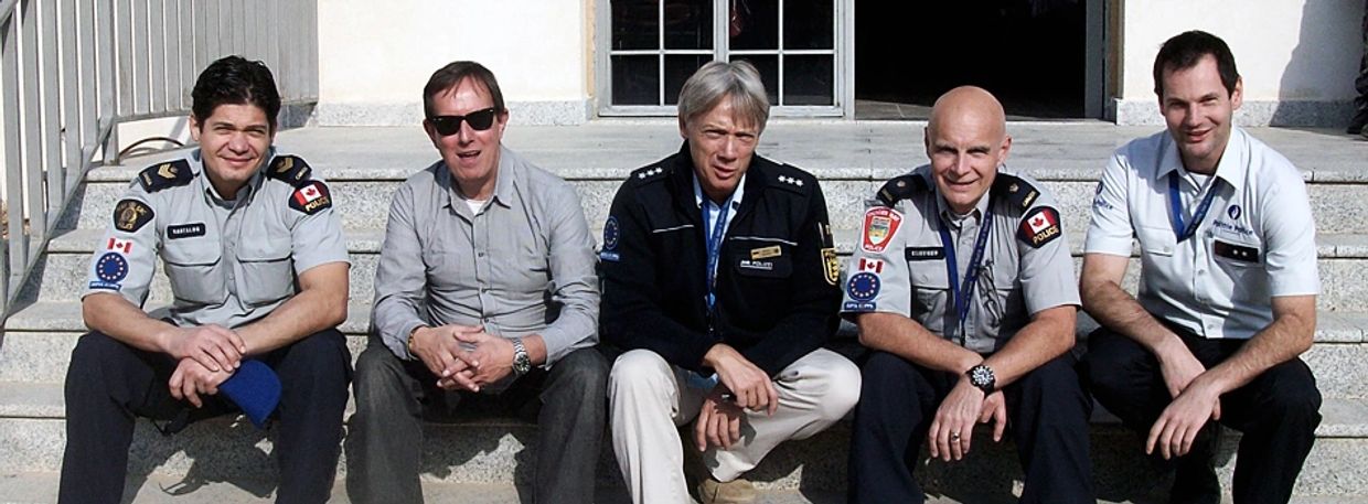 Five men sitting on outdoor steps, three in uniform.